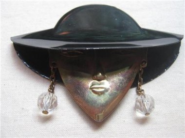 This is a face brooch. You would pin it to your blouse, just below your actual face. Nobody knows why. By DressLikeAMovieStar