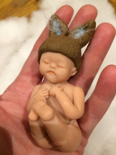 This is intended as a baby shower gift. My daughter once shat herself so hard, it shot up the back of her diaper and hit her in the head. The cleanup is a blur, but I'm pretty sure I didn't stop to form bunny ears with it first. By FimoAlive