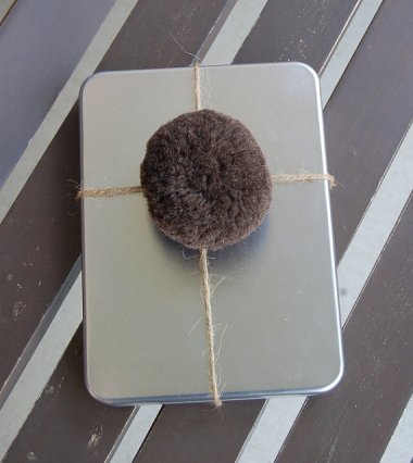 This is a wool pompom to use in place of a bow. Just looks like Santa left you a different kind of present.